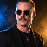 ChatGPT AI generated dramatic studio portrait of a man with slicked-back hair and a mustache, wearing gold sunglasses and a black blazer under dual-tone smoke lighting.