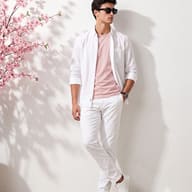 Men's Spring Fashion Cherry Blossom AI Photo Editing Prompt. AI generated portrait of a young man in a white shirt, pink t-shirt, and white pants, leaning against a wall with cherry blossom shadows.
