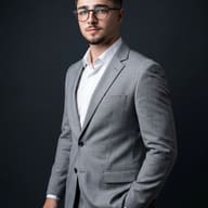 Gemini AI Generated Executive studio photo of a man in a tailored light gray suit and white shirt, posing with his hand in his pocket on a dark seamless backdrop.