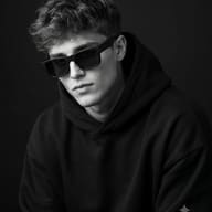 Monochrome Boy Hoodie Portrait AI Photo Editing Prompt. AI generated studio portrait of a young man wearing a black hoodie and dark sunglasses against a black background.
