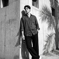AI-generated high-contrast monochrome editorial photo of a stylish young man posing confidently against a modern wall corner under bright sunlight.