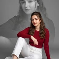 AI generated creative portrait featuring a young woman in a red ribbed sweater and white jeans sitting on a grey floor, with a large, translucent black-and-white double-exposure portrait of her face in the background.