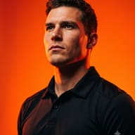 Cinematic Male Portrait AI Photo Editing Prompt. AI generated studio portrait of a focused man in a black polo shirt illuminated by dramatic orange lighting against a vibrant orange background.