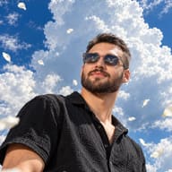 ChatGPT Image Prompt: Heroic perspective picture of a bearded man in a textured black shirt looking at a vibrant blue sky filled with massive white clouds and falling petals.