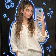 AI Image prompt: Casual indoor mirror selfie of a young woman holding a smartphone, decorated with a vibrant blue neon body outline and hand-drawn glowing teddy bear and star doodles.