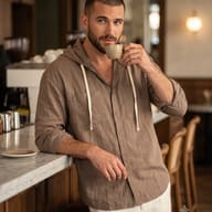 Casual Cafe Lifestyle Photography AI Prompt. AI generated lifestyle portrait of a bearded man in a brown linen hoodie drinking espresso at a marble cafe counter.