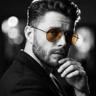 Gemini AI Prompt: Cinematic studio picture of a bearded man in monochrome with bright amber sunglasses.
