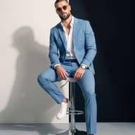 AI Prompt: Cinematic studio image of a confident man with a buzz cut wearing a sky-blue suit and white leather sneakers.