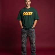 Young Man in Green Graphic Tee and Graffiti Jeans Studio Portrait AI Photo Editing Prompt. AI generated studio portrait of a handsome bearded man wearing an oversized green t-shirt and printed grey jeans standing with hands in pockets against a solid maroon background.