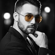 AI Photo Editing Prompt: Black and white picture of a confident man wearing amber sunglasses against blurred studio lights.