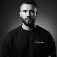 B&W Portrait Photography AI Photo Editing Prompt. AI generated black & white studio portrait of a bearded man wearing a black crewneck sweatshirt with text against a gradient background.