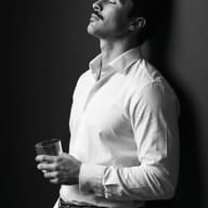 Black and White Male Portrait with Glass AI Photo Editing Prompt. AI generated monochrome portrait of a man with eyes closed leaning back, holding a rocks glass.
