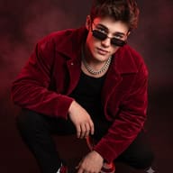 Edgy Streetwear AI Photo Prompt. AI generated studio portrait of a young man crouching in a red velvet jacket and chain against dark red fog.