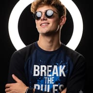 Ring Light DP AI Photo Editing Prompt. AI generated profile picture of a smiling man in sunglasses and printed tee against a ring light.
