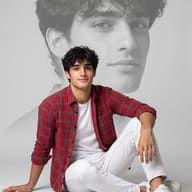 AI generated conceptual portrait of a young man in a red plaid shirt sitting on the floor with a large, faded close-up image of his own face in the background.