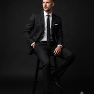 Seated Man in Black Suit Studio Portrait AI Photo Editing Prompt. AI generated studio portrait of a handsome man in a formal black suit sitting on a black stool against a dark background.
