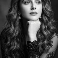 AI Photo Prompt: Monochrome photo of a thoughtful woman wearing sheer dark sleeves and a beaded cuff bracelet.