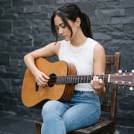 AI Photo Prompt: Minimalist lifestyle image of a girl looking down at her acoustic guitar strings with a charcoal grey background.