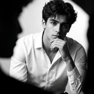 AI Image Prompt: Cinematic monochrome portrait of a young guy resting his chin on his hand with intense lighting creating a frame within a frame effect.