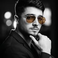 AI Photo Prompt: Film-noir style photo of a man in a dark jacket with a color splash of amber aviator lenses.