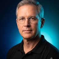 AI generated studio portrait of a middle-aged man with short gray hair and thin glasses, wearing a black polo shirt, against a dark blue and teal gradient background.