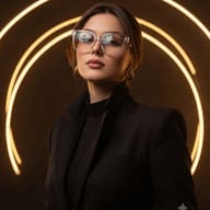 Gemini AI Generated High-contrast portrait of a young woman with brown hair and clear eyeglasses, wearing a black tailored blazer with bright golden neon arcs behind her.