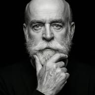 Thoughtful Bearded Man B&W AI Photo Editing Prompt. AI generated high-contrast studio portrait of an elderly bald man with a full white beard resting his hand on his chin.