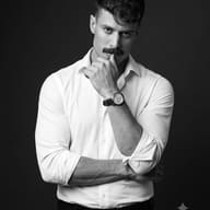 Monochrome Man Studio Portrait AI Photo Editing Prompt. AI generated studio portrait of a mustached man in a white shirt and watch, posing thoughtfully against a dark background.