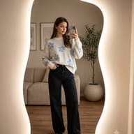 Aesthetic lifestyle mirror selfie portrait of a woman in a floral sweater AI Photo Editing Prompt. AI generated lifestyle photography of a young stylish woman taking a phone selfie in a glowing wavy mirror inside a minimalist room.