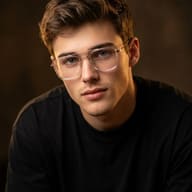 AI generated studio portrait of a young man wearing clear-framed glasses and a black t-shirt against a warm dark background.