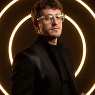 AI Image Prompt: Modern urban fashion portrait of a young man with short wavy hair, wearing clear glasses and a black jacket, highlighted by bright circular neon lights.