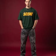 Young Man in Green Graphic Tee and Graffiti Jeans Studio Portrait AI Photo Editing Prompt. AI generated studio portrait of a handsome bearded man wearing an oversized green t-shirt and printed grey jeans standing with hands in pockets against a solid maroon background.