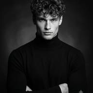 AI generated black and white studio portrait of a curly-haired man in a black turtleneck posing with crossed arms.