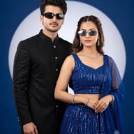 Modern South Asian Couple in Sherwani and Lehenga AI Photo Editing Prompt. AI generated studio portrait of a stylish young South Asian couple in a black sherwani and blue sequined lehenga, both accessorized with sunglasses and fine diamond jewelry.