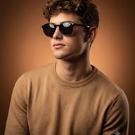Warm Tone Studio Portrait AI Photo Editing Prompt. AI generated studio portrait of a young man with short curly hair wearing dark round sunglasses and a light brown sweater.