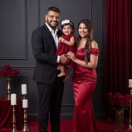 Luxury Formal Family Portrait AI Photo Editing Prompt. AI generated portrait of a family of three in formal attire posing on a red carpet against a dark gray wall with red roses and curtains.