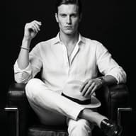 Man in White Linen on Leather Chair AI Photo Editing Prompt. AI generated monochrome studio portrait of a man in white linen clothing sitting in a black leather armchair while holding a straw hat.